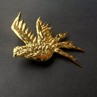 Broche dorado en forma de ave con detalles de cristales brillantes