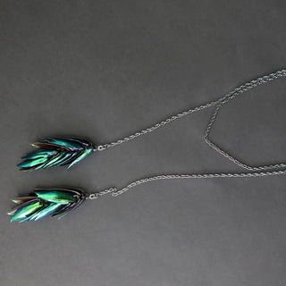 Corbatero de plumas de mayate con cadena en plata oxidada y detalles pavé.